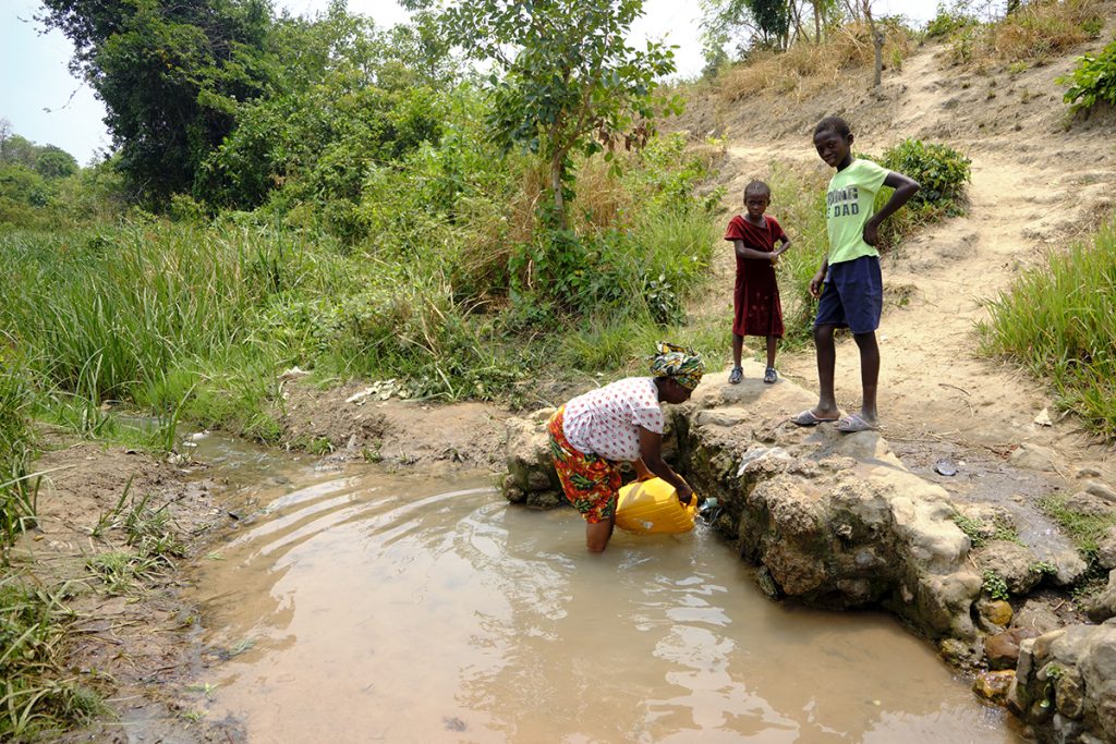 Mujer recogiendo agua (contaminada) para beber, cocinar, etc.